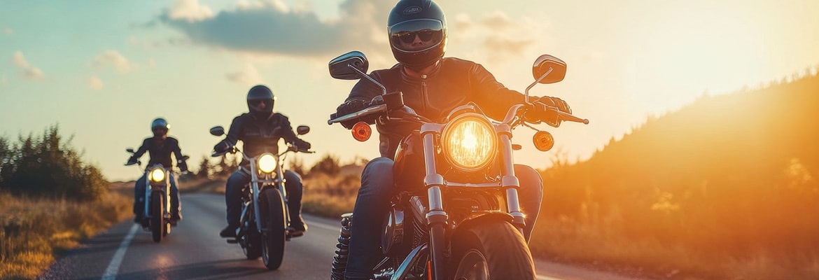 Three motorcycle riders on the road at sunset.